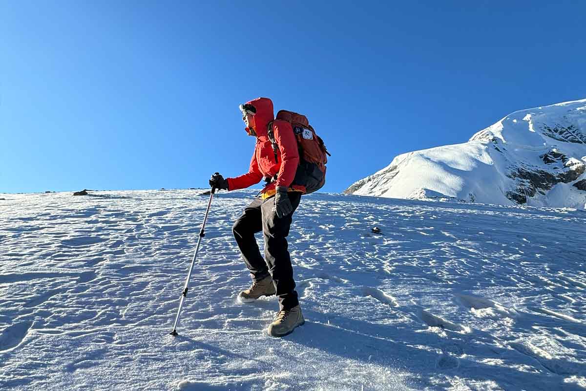 Trekker in insulated jacket and boots crossing Thorong La Pass